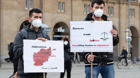07 April 2021, Saxony, Dresden: Protesters hold signs during a rally called by the Dresden Afghanistan Association and the Saxon Refugee Council against collective deportations to Afghanistan on the Altmarkt. Photo: Sebastian Kahnert/dpa-Zentralbild/dpa