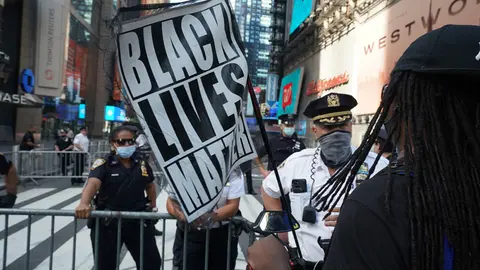 FILED - A woman holds a Black Lives Matter flag as she speaks with police officers during a Black Lives Matter protest at Times square following the death of George Floyd, an African American man who was killed on 25 May while in police custody in the US city of Minneapolis. Photo: Bryan Smith/ZUMA Wire/dpa