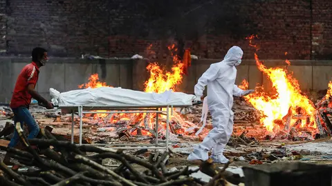 09 May 2021, India, New Delhi: A relative and a health worker carry a body of Coronavirus (Covid-19) victim during a cremation at a crematorium in New Delhi. Photo: Amarjeet Kumar Singh/SOPA Images via ZUMA Wire/dpa