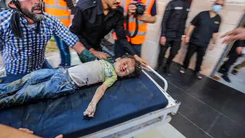 13 May 2021, Palestinian Territories, Gaza City: People transport the body of a Palestinian child who was killed after an Israeli airstrike on Gaza City to a hospital amid the escalating flare-up of Israeli-Palestinian violence. The Ministry of Health in the Gaza Strip said that at least 109 Palestinians, including 28 children, were killed in the recent Israeli airstrikes. Photo: Mahmoud Issa/Quds Net News via ZUMA Wire/dpa
