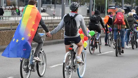 FILED - Participants of a bicycle rally of this year's Christopher Street Day (CSD) cycle through the city of Cologne with a rainbow flag. Instead of a large parade, which fell victim to the Corona pandemic, lesbians, gays and transsexuals marched through the streets in a bicycle demonstration during Corona Year to protest for their cause. Photo: Roberto Pfeil/dpa
