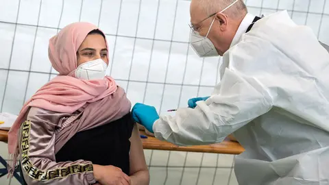 14 May 2021, Berlin: A woman receives a Johnson & Johnson vaccine against Coronavirus by Dr. Fatmir Dalladaku in the gym of a school in Neukoelln, where a focus vaccination against Corona is taking place. Photo: Bernd von Jutrczenka/dpa