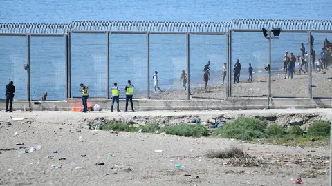 19 May 2021, Spain, Ceuta: Agents watch from the fence that separates Ceuta from Morocco the arrival of migrants. Photo: Antonio Sempere/EUROPA PRESS/dpa
