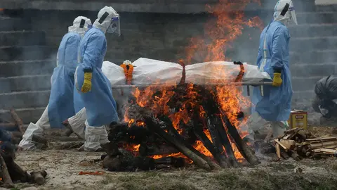04 May 2021, Nepal, Kathmandu: Men wearing personal protective suits carry the body of a COVID-19 victim for cremation on the bank of Bagmati River. Photo: Dipen Shrestha/Zuma Press/dpa