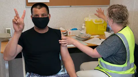 16 June 2021, Canada, Delta: A man gives the victory sign as he receives a dose of a COVID-19 vaccine at a truck stop. Photo: Jonathan Hayward/The Canadian Press via ZUMA/dpa