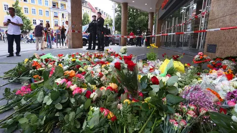 26 June 2021, Bavaria, Wuerzburg: Candles and flowers are placed in front of a closed and cordoned off department store in downtown Wuerzburg, where a fatal knife attack took place last night leaving three people dead and seven injured. Photo: Karl-Josef Hildenbrand/dpa