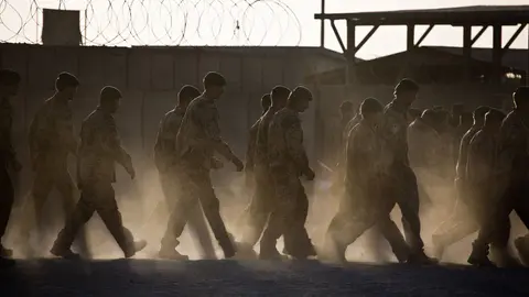 FILED - 03 October 2013, Afghanistan, Kunduz: Bundeswehr soldiers walk across the dusty deployment site after a roll call. Germany has withdrawn the last Bundeswehr soldiers from Afghanistan, ending its mission in the country, sources told DPA on Tuesday evening. Photo: Michael Kappeler/dpa
