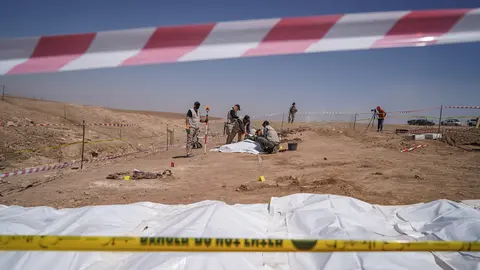 FILED - 13 June 2021, Iraq, Al-Humaydat: Members of expert teams take part in the opening of a mass grave and the exhumation of the remains of victims who were killed and buried by the so-called Islamic State (IS) terror group back in 2014. More than 500 people, predominantly Shia Muslims, where executed and buried in the mass grave during an IS attack on the Badush Prison on 10 June 2014. The mass grave, which was first discovered in 2017, is located in the village of Al-Humaydat, 30 km west of the city of Mosul, a former IS stronghold in Iraq's northern Nineveh Governorate. Photo: Ismael Adnan/dpa