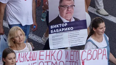 FILED - People walk in Minsk's Independence Square during a demonstration against Belarusian ruler Alexander Lukashenko, carrying a banner with the photo of Viktor Babariko, who wanted to run against Lukashenko in the presidential election. Photo: Ulf Mauder/dpa