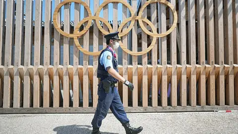 19 July 2021, Japan, Tokyo: A police officer walks past Olympic rings at the entrance to Olympic Village. The Olympic Village is a housing development that will house the participants of the 2020 Olympic Games. Tokyo 2020 Olympic Games will be held from 23 July to 8 August 2021. Photo: Michael Kappeler/dpa