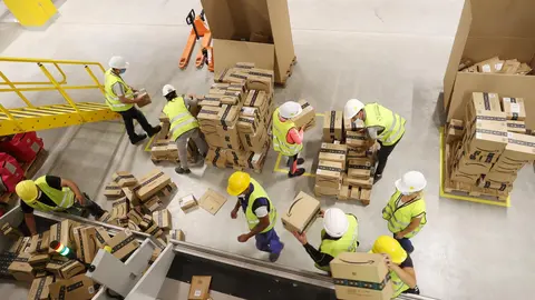 21 July 2021, Thuringia, Gera: Employees transport shipping boxes during a trial run at the logistics hall of the new Amazon logistics centre in Gera, a new site by the e-commerce company that will create around 1000 jobs. Photo: Bodo Schackow/dpa-zentralbild/dpa