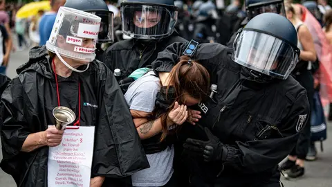 01 August 2021, Berlin: Policemen detain a woman taking part in an unannounced demonstration against the Coronavirus measures despite a ban on protests. Photo: Fabian Sommer/dpa