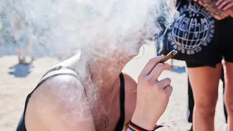 14 August 2021, Berlin: A demonstrator smokes a joint during the Hanfparade 2021 to call for legalizing cannabis use in Germany. Photo: Annette Riedl/dpa
