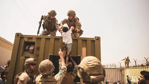 20 August 2021, Afghanistan, Kabul: British, Turkish and US soldiers assist a child during the evacuation of civilians at Hamid Karzai International Airport. Photo: Ssgt. Victor Mancilla/U.S. Marin/Planet Pix via ZUMA Press Wire/dpa