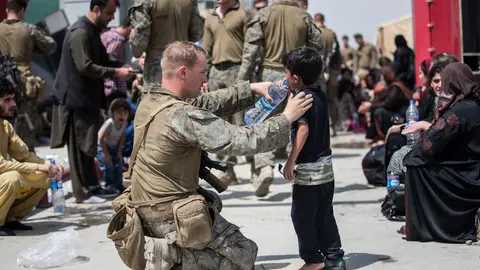20 August 2021, Afghanistan, Kabul: A US Marine soldier provides fresh water to a child as Afghan civilians wait to board an aircraft during the evacuation process at Hamid Karzai International Airport. Photo: -/US Marines via ZUMA Press Wire Service/dpa