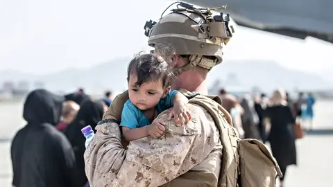 HANDOUT - 22 August 2021, Afghanistan, Kabul: A US marine soldier carries a young boy at the Hamid Karzai International Airport during the evacuation of civilians following the Taliban takeover. Photo: Sgt. Samuel Ruiz/U.S. Marine/Planet Pix via ZUMA Press Wire/dpa - ACHTUNG: Nur zur redaktionellen Verwendung und nur mit vollständiger Nennung des vorstehenden Credits