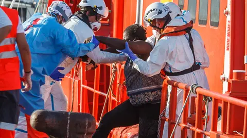 25 August 2021, Spain, Arguineguin: Employees of the sea rescue service help a migrant to disembark the vessel Guardamar Talia. The Coast Guard spotted 46 sub-Saharan migrants south of Arguineguin. Among the occupants of the boat were 30 men, 14 women and two minors. Photo: Europa Press/EUROPA PRESS/dpa