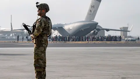 20 August 2021, Afghanistan, Kabul: A US Air Force soldier stands guard as evacuees are loaded onto a C-17 Globemaster III aircraft during the evacuation process at Hamid Karzai International Airport. Photo: Sra Taylor Crul/U.S. Air/Planet Pix via ZUMA Press Wire/dpa