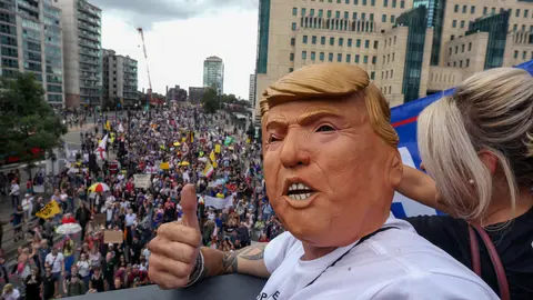 28 August 2021, United Kingdom, London: A protester wears a Donald Trump mask, during the medical freedom march against Vaccine passports, mandatory vaccines for care workers and vaccines for children. Photo: Martin Pope/SOPA Images via ZUMA Press Wire/dpa