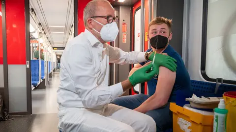 30 August 2021, Berlin: Christian Gravert, chief medical officer of the Deutsche Bahn, vaccinates a man in a special train of the S-Bahn, in which vaccinations with the vaccine of the manufacturer Johnson & Johnson are offered. Photo: Christophe Gateau/dpa