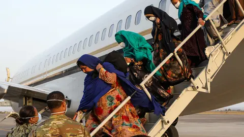 HANDOUT - 26 August 2021, Italy, Sigonella: Servicemen assist Afghan evacuees as they disembark a plane at the Sigonella Naval Air Station Airport in the midst of the Taliban takeover. Photo: Mc2 Claire Dubois/U.S. Navy/Planet Pix via ZUMA Press Wire/dpa - ATTENTION: editorial use only and only if the credit mentioned above is referenced in full