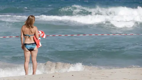 02 September 2021, Spain, Manacor: A woman stands on the closed off beach of Cala Mendia in Manacor on Mallorca. Photo: Clara Margais/dpa