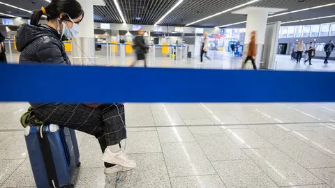 FILED - A tourist sits on her suitcase and waits for a return flight to her home country from Frankfurt. A US entry ban for Europe - now set to fall away for those who are vaccinated against Covid-19 - has disrupted travel the last two years. Photo: Andreas Arnold/dpa
