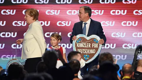 24 September 2021, Bavaria, Munich: Armin Laschet , candidate for Chancellor of the CDU/CSU party and Prime Minister of North Rhine-Westphalia, and Chancellor Angela Merkel (CDU) are on stage at the official end of the election campaign of the CDU and CSU in the Festhalle at the Nockherberg. Laschet is holding a gingerbread heart with the sugar icing inscription "Chancellor for Germany". Photo: Matthias Balk/dpa