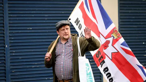 17 September 2021, United Kingdom, Belfast: An anti Northern Ireland Protocol protester holds a flag during a rally against the post-Brexit arrangements in Newtownards Road. Photo: Peter Morrison/PA Wire/dpa