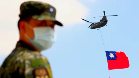 A soldier stands guard on Monday as a Chinook Helicopter carrying a tremendous Taiwan flag flies over a military camp, part of a rehearsal for the flyby performance for Taiwan's Double-Ten National Day Celebration. Taiwan condemned China on Saturday for sending 38 warplanes into its airspace the day before, the largest ever incursion reported. Photo: Daniel Ceng Shou-Yi/ZUMA Press Wire/dpa