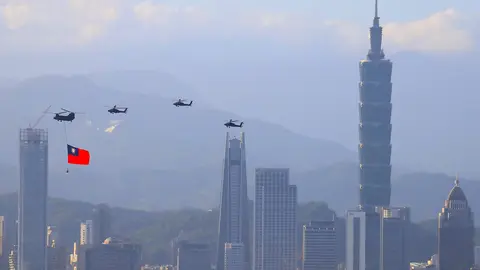 05 October 2021, Taiwan, New Taipei City: A military helicopter carrying a tremendous Taiwan flag conducts a flyby rehearsal with other helicopters ahead of the Double-tenth National Day celebration, near Taipei 101, amid China's growing military threats. Photo: Daniel Ceng Shou-Yi/ZUMA Press Wire/dpa