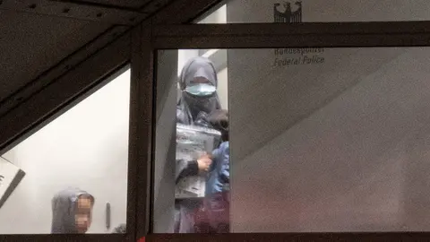 A veiled woman wearing a mask enters a screened-off area of the Federal Police at Frankfurt Airport from the gangway of a charter plane with two small children. In an action that was initially kept secret, the German government, in cooperation with the US Army, had taken a total of eight German female supporters of the terrorist militia "Islamic State" (IS) and their 23 children from a prison camp in Syria as part of a humanitarian operation. The women were brought to Germany via Kuwait on a charter plane, where almost all of them were immediately taken into custody. Photo: Boris Roessler/dpa