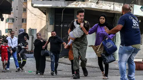 Civilians run for cover after gunfire erupted at a protest by supporters of the Shiite Hezbollah movement against the judge investigating the city's port port blast, near the former civil war front-line between Muslim Shiite and Christian areas. At least six people were killed and 30 injured in Beirut as gunfire broke out at a protest against the judge investigating last year's blast at the city's port, the Lebanese Red Cross said. Photo: Marwan Naamani/dpa.