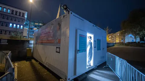 08 November 2021, Hessen, Frankfurt/Main: An employee of a Coronavirus test centre stands in the open door to the container in which the test cabins are housed. Photo: Boris Roessler/dpa