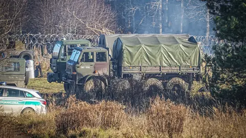 Polish army vehicles stand on the barbed wire border between Poland and Belarus near the Kusnica border crossing. The migration crisis at the Poland-Belarus border with refugees trying to enter the European Union via Belarus worsened on Monday, with Belarusian authorities saying that many hundreds of migrants had arrived at the border, and Poland reporting that some had already tried to break through. Photo: Michael Kappeler/dpa.