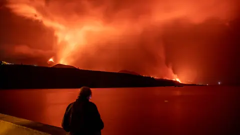 FILED - 09 November 2021, Spain, La Palma: A person stands on the Los Guirres beach and watches lava flowing out of Cumbre Vieja volcano, during its eruption in La Palma on the Canary Islands. Photo: Kike Rincón/EUROPA PRESS/dpa.