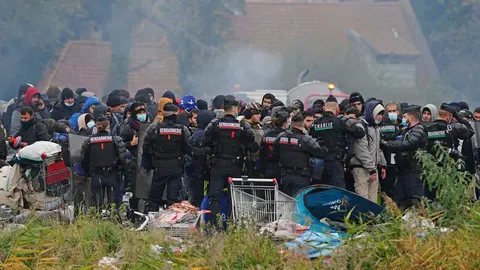 16 November 2021, France, Dunkirk: Migrants wait at a makeshift camp on the site of a former industrial complex in Grande-Synthe, as French police are evacuating migrants from the site, where at least 1,500 people had gathered in hopes of making it across the English Channel to Britain. Photo: Gareth Fuller/PA Wire/dpa.