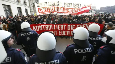 20 November 2021, Austria, Vienna: Policemen stand guard as people march down the Heldenplatz during a protest against the upcoming nationwide coronavirus lockdown. Photo: Florian Wieser/APA/dpa.