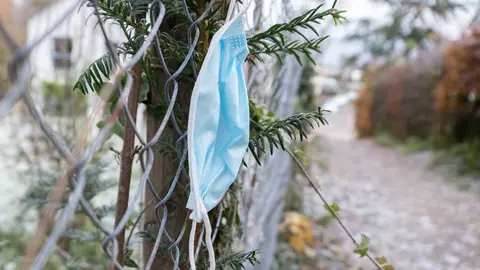 24 November 2021, Baden-Wuerttemberg, Stuttgart: A dangling mask is seen on a fence along a sidewalk in Stuttgart, Germany. Photo: Bernd Weißbrod/dpa.