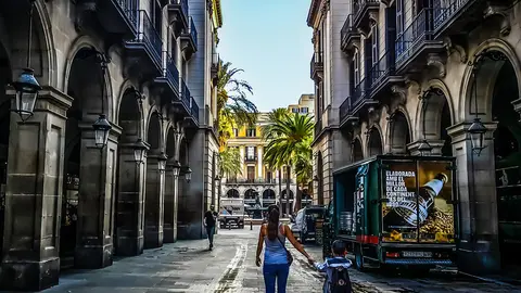 A woman walks with a child through the center of Barcelona. Photo: Pixabay.