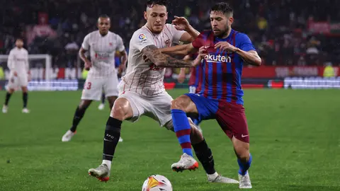 21 December 2021, Spain, Sevilla: Barcelona's Jordi Alba (R) and Sevilla's Lucas Ocampos battle for the ball during the Spanish La Liga soccer match between Sevilla and Barcelona at Ramon Sanchez-Pizjuan Stadium. Photo: Jose Luis Contreras/DAX via ZUMA Press Wire/dpa.