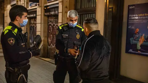 24 December 2021, Spain, Barcelona: Police officers fine a person after checking his papers and reasons to be outside during curfew time that was imposed as part of coronavirus measures. Photo: Kike Rincón/EUROPA PRESS/dpa.