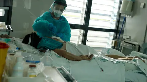 27 December 2021, Spain, Palma: A nurse cares for a patient in the intensive care unit of the main hospital Son Espases for coronavirus patients. Photo: Clara Margais/dpa.