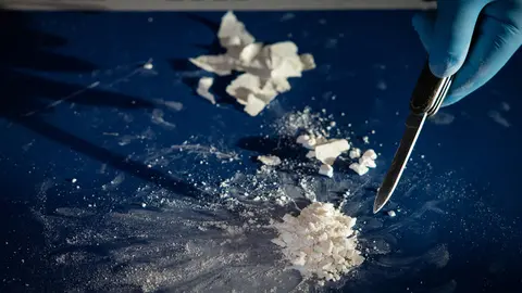 16 December 2021, Hamburg: A customs officer diplays pressed and highly concentrated cocaine from after a large cocaine stash was seized, during a press conference of the Hamburg customs. Photo: Christian Charisius/dpa.