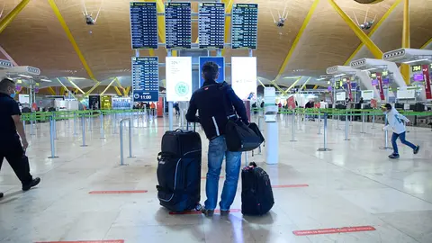 05 January 2022, Spain, Madrid: A traveller stands with his luggage as he looks at the display board at Adolfo Suarez Airport in Madrid. Photo: Jesús Hellín/EUROPA PRESS/dpa.