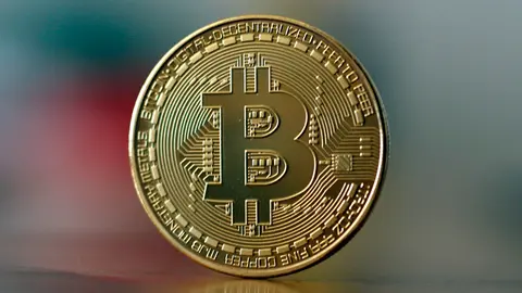 FILED - Illustration - A bitcoin is pictured on a table. The International Monetary Fund (IMF) has urged El Salvador to abandon Bitcoin as a means of payment. Photo: Ina Fassbender/dpa.