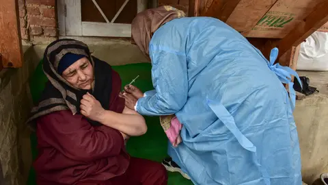 24 January 2022, India, Budgam: A health worker administers a dose of Covishield Coronavirus vaccine to a woman during a door to door vaccination drive at a remote village in Budgam district. Photo: Saqib Majeed/SOPA Images via ZUMA Press Wire/dpa.