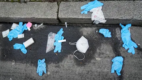 18 January 2022, Berlin: Disposable gloves, a mask and used COVID-19 rapid antigen testing kits lie on the street in front of a coronavirus test center. Photo: Kay Nietfeld/dpa.