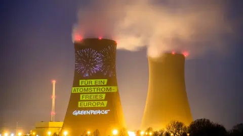 dpatop - 2021: A projection by the environmental protection organization Greenpeace shines on the German nuclear power plant Grohnde (long exposure). A debate has flared up in the EU about the climate impact of nuclear power plants. Photo: Julian Stratenschulte/dpa.