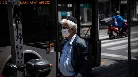 FILED - 20 April 2020, Israel, Tel Aviv: A man wearing a face mask walks on a street near a public bus. The number of serious Covid-19 cases in Israel continues to rise to record highs, with 1,263 reported on Sunday. Photo: Ilia Yefimovich/dpa.